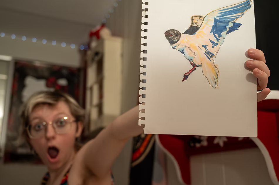 Willow holding up a drawing of a bird he made.